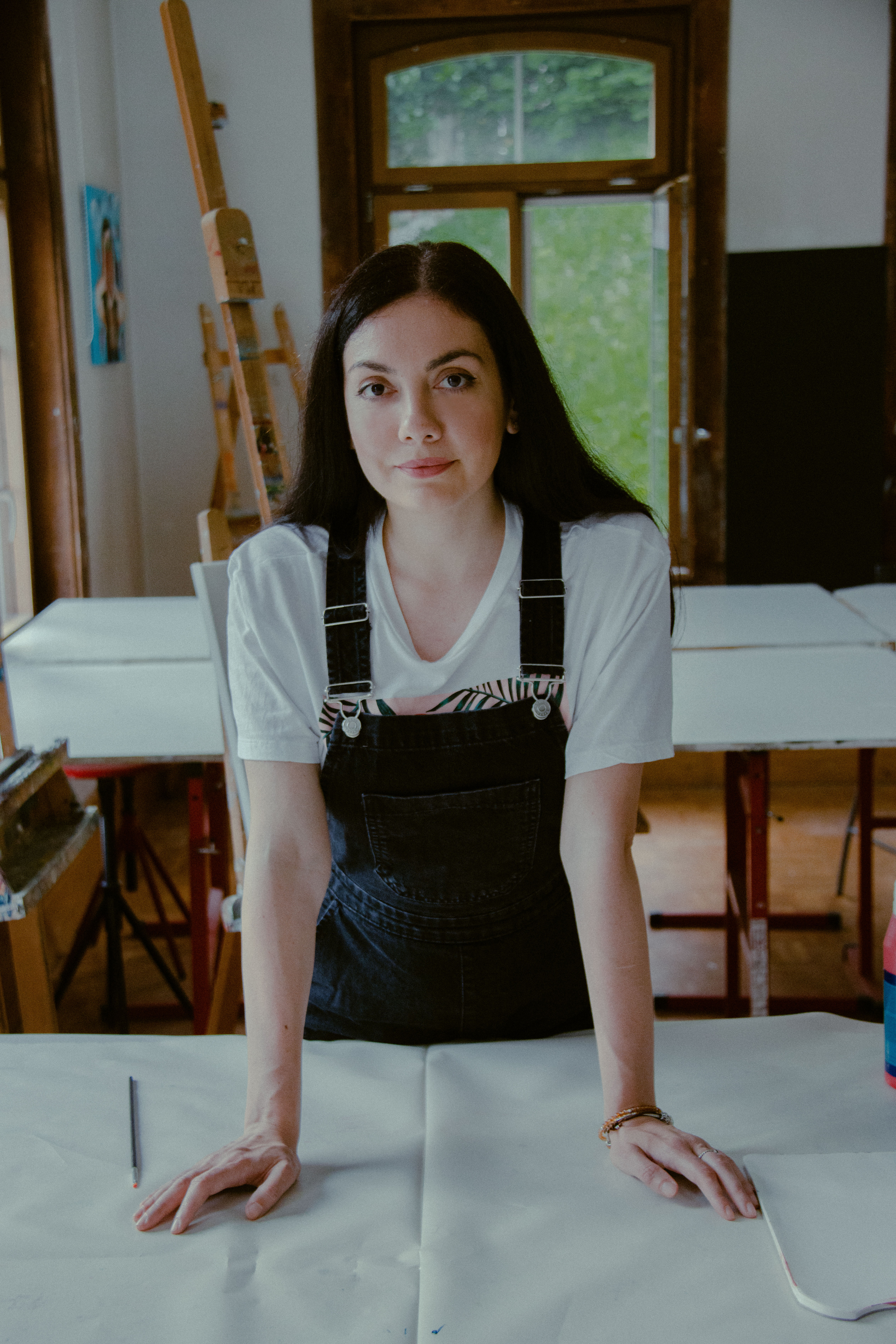 Amalia Maciuca hat langes, dunkles Haar und trägt eine Arbeiter-Latzhose über einem weissen Shirt.
