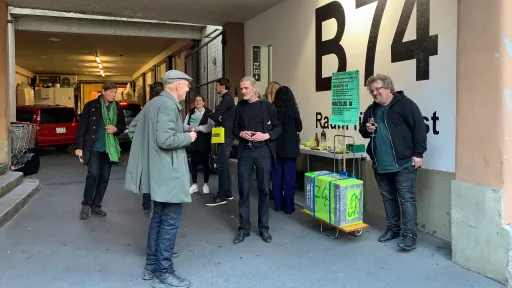 Mehrere Personen stehen vor dem Eingang der Galerie B74 und halten Gläser in der Hand.