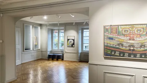 Ein Raum mit Parkettboden. An der Wand hängen beleuchtete Malereien