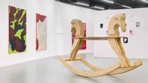Ausstellungsansicht «Love» Kunsthalle Luzern, 2025 Foto : Kilian Bannwart, 2025. Ein gigantisches, zweiseitiges Schaukelpferd, dahinter grosse, bunte Malereien