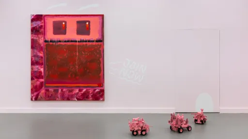Marco Russo Serie «Join Now», 2025 Foto : Kilian Bannwart, 2025, eine Installation mit einer Malerei eines roten, abstrakten Gesichts, das ruft "join now". Kleine rosa Panzer-Skulpturen fahren in einer Parade davor.