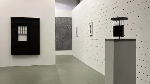 Bernard Voïta - Insomnie Géométrique bei Edizioni Galleria Periferia. Links eine Wandskukptur einer schwarzen Fassade, rechts ein Sockel mit einer kleinen schwarzen Skulptur darauf