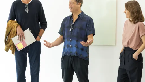 Drei Menschen unterhalten sich über eine grüne Malerei im Hintergrund